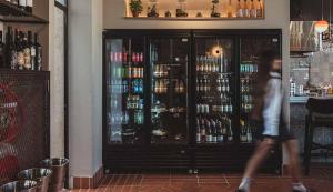 a woman walking past a bar with a glass door at Hotel Shoshana - Adults Only in Eilat
