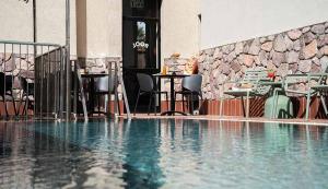 a swimming pool with chairs and tables in front of a building at Hotel Shoshana - Adults Only in Eilat