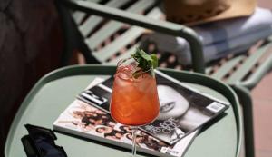 a drink sitting on a table with a magazine at Hotel Shoshana - Adults Only in Eilat