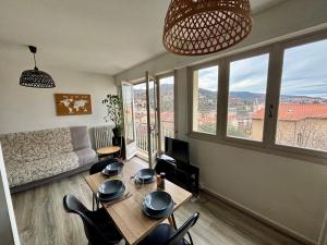 a living room with a table and chairs and windows at Belle vue à 500m des thermes - climatisé in Royat