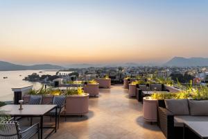a rooftop patio with tables and chairs and a view of the city at My Downtown - The Red Pier in Udaipur +131 photos