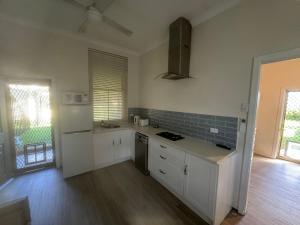a kitchen with white cabinets and a counter top at Hotel Koorawatha garden unit - ground floor in Koorawatha +9 photos