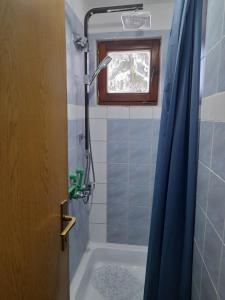 a bathroom with a tub and a shower with a blue curtain at Jahorinska planinska kuća in Jahorina