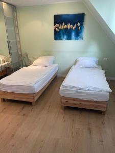 two twin beds in a room with a painting on the wall at Aparthotel Messe Flughafen in Düsseldorf