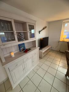 a kitchen with white cabinets and a flat screen tv at Strandgut in Fehmarn