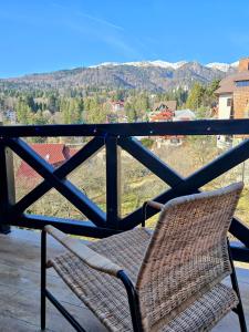 a wicker chair sitting on a balcony with a view at Vila Ferdinand Apartments in Sinaia
