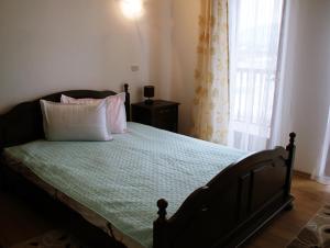 a bedroom with a bed with pillows and a window at Pensiunea Crimar in Ilteu