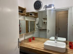 a bathroom with a sink and a clock on the wall at Apartment Pegase Phenix-38 by Interhome in Le Corbier