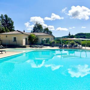 a swimming pool with blue water in front of a house at Les Villas du Vendoule in Saint-Maurice-dʼArdèche