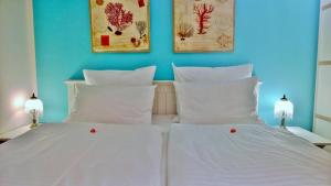 - un lit avec 2 oreillers blancs et 2 photos sur le mur dans l'établissement Ostsee Ferienappartement Dierhagen-Strand, à Dierhagen