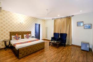 a bedroom with a bed and a chair and a television at FabHotel Pulse Impulse in New Delhi