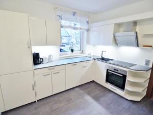 a kitchen with white cabinets and a sink and a window at Appartements Peter in Sankt Kanzian
