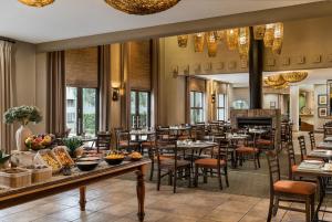 a restaurant with tables and chairs and a fireplace at Protea Hotel by Marriott Bloemfontein Willow Lake in Bloemfontein +34 photos