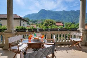 a table and chairs on a balcony with mountains in the background at Casa Miralago in Castelveccana