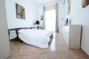 a white bedroom with a bed and a television at Domus61 in Marsala
