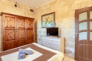 a bedroom with a bed and a tv and a door at Traditional entire maisonette close to airport in Birżebbuġa