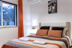 ein Schlafzimmer mit einem Bett mit zwei Kissen und einem Fenster in der Unterkunft Villa Figueira in Portimão