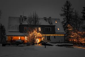 a house decorated with christmas lights in the snow at Butikowe apartamenty w Sudetach - TRZY MORZA - pod górą Trójmorski Wierch in Jodłów