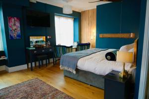 a bedroom with blue walls and a bed and a desk at Arosfa Harbourside Aberaeron in Aberaeron