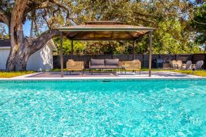 a swimming pool with a gazebo and chairs next to a pool at 6 Bedrooms, Two Villas, Heated Pool, 2mil to Downtown in Naples +34 photos