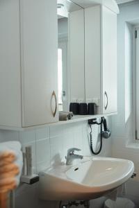 ein weißes Badezimmer mit Waschbecken und Spiegel in der Unterkunft Gasthof Schütthof in Neukirchen am Großvenediger