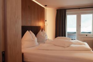 ein Schlafzimmer mit einem Bett mit weißen Kissen und einem Fenster in der Unterkunft Gasthof Schütthof in Neukirchen am Großvenediger