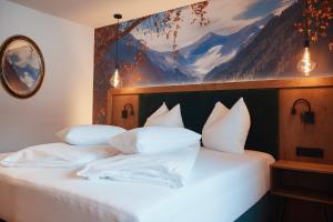 ein Schlafzimmer mit einem Bett mit weißen Kissen und einem Gemälde in der Unterkunft Gasthof Schütthof in Neukirchen am Großvenediger
