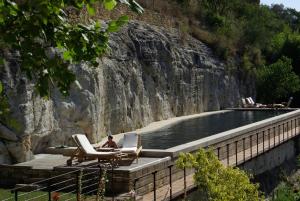 un uomo seduto su una sedia accanto alla piscina di Maison d'amis a Beynac-et-Cazenac Altre 5 foto