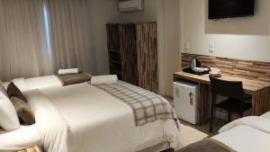 a hotel room with two beds and a desk at Novo Hamburgo Business Hotel in Novo Hamburgo