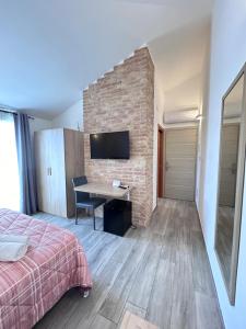 a bedroom with a desk and a brick wall at Affittacamere Su Caboni in Tortolì