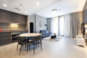 a kitchen and living room with a table and chairs at 1BR The Modern Al Jada Home by Blue Cloud Holidays in Sharjah