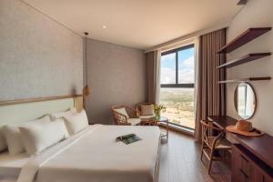 a bedroom with a bed and a desk and a window at Apec Mandala Chambay Mui Ne - Oceanic Studio in Mui Ne +156 photos