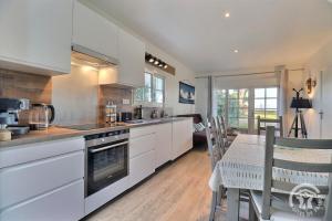 a kitchen with white cabinets and a dining table at Ty gwenn in Cancale +17 photos