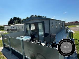 a tiny house with a table and a pool at The Retreat 39 - Hot tub Mini Lodge - Golden Palm - pet friendly, WiFi, central heating, bed linen - Meadow Lakes Caravan & Lodge Hire in Chapel Saint Leonards