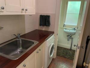 a kitchen with a sink and a washing machine at The Garden Gatehouse in Aldgate +16 photos