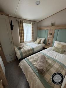 a bedroom with two beds and a window at The Retreat 39 - Hot tub Mini Lodge - Golden Palm - pet friendly, WiFi, central heating, bed linen - Meadow Lakes Caravan & Lodge Hire in Chapel Saint Leonards
