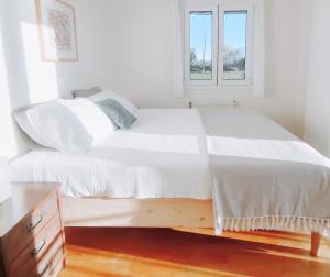 a white bed in a room with a window at KALAMIES - Secluded Beach Apartments in Skala