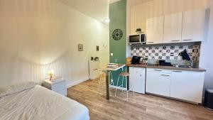 a bedroom with a bed and a kitchen with white cabinets at Le petit Verdier Mosellan - Thionville - 2P in Thionville