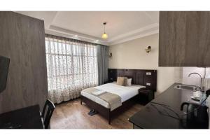 a bedroom with a bed and a table and a desk at Hemak Suites in Nairobi