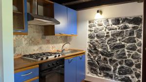 a kitchen with blue cabinets and a stone wall at Antico Pistacchieto GUEST HOUSE in Bronte