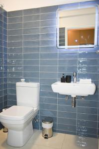 a blue tiled bathroom with a toilet and a sink at Comfort Zone Suites - Hidas 2 in Windhoek