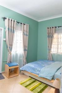 カンパラにあるesteez houseの青い壁のベッドルーム1室、ベッド1台、窓が備わります。