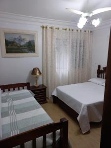 a bedroom with two beds and a window at Apto Aconchegante Piscina 2 Vagas in Guarujá