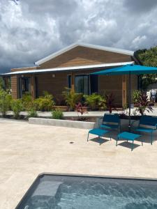 a house with blue chairs and a swimming pool at O Coeur de l ouest bungalow Vanille Bourbon in Saint-Paul