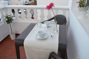 einen Tisch mit zwei Tassen und eine Blume auf dem Balkon in der Unterkunft Elena Beach House Lanzarote in Playa Honda