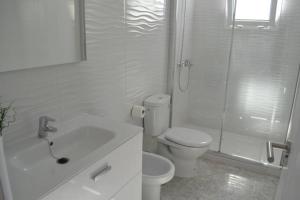 Un baño blanco con inodoro y ducha. en Elena Beach House Lanzarote, en Playa Honda 11 fotos más