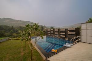 a swimming pool on the side of a house at SaffronStays Prisma Luxury 8 bedroom Villa with Pool in Lonavala in Malavli