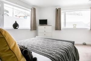 Un dormitorio con una cama y un televisor y ventanas. en Life of Riley, en St Ives