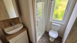 a small bathroom with a toilet and a sink at The Retreat 8 Lodge - Hot tub, WiFi, pet friendly, bath - Golden Palm Resort - Meadow Lakes Caravan & Lodge Hire in Chapel Saint Leonards +7 photos