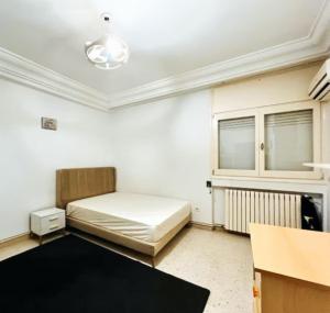 a small room with a bed and a table at Belle Appartement pour Familles S2 El Nasser 1 Ariana in Ariana